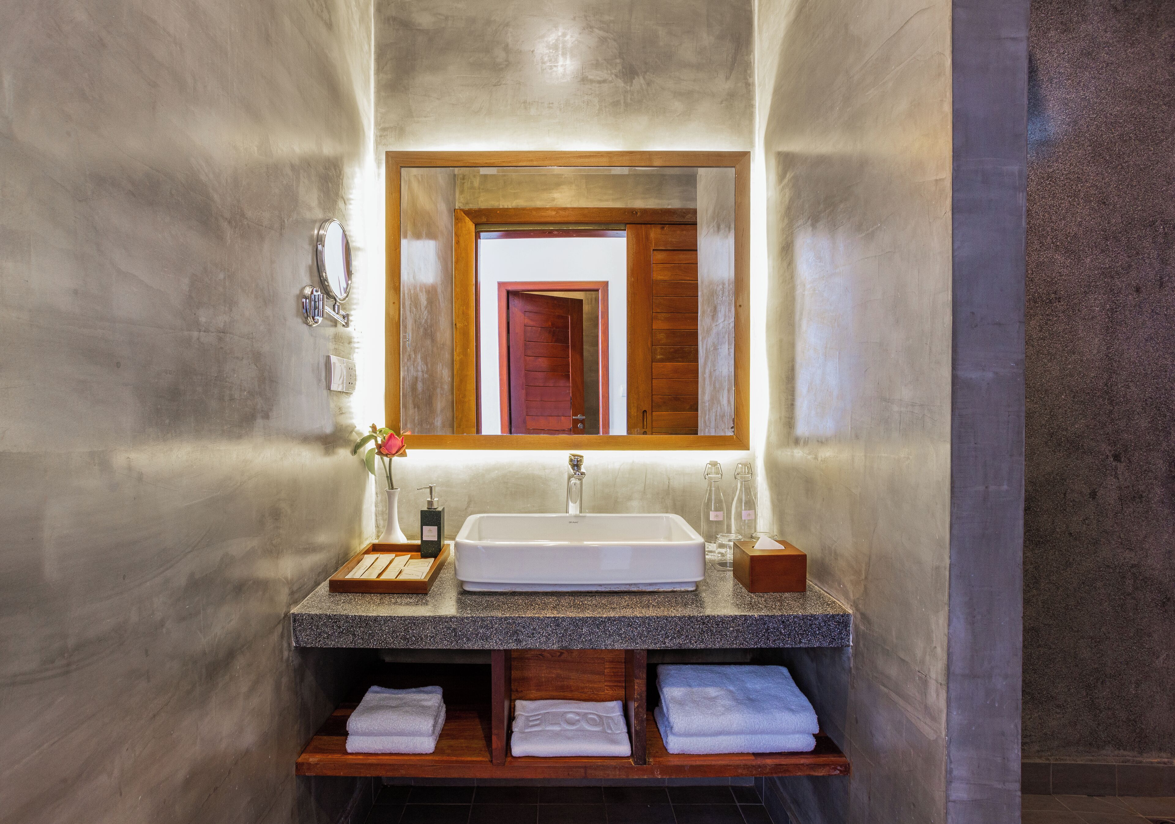 A bathroom with a rectangular sink, a mirror, and a wooden vanity.