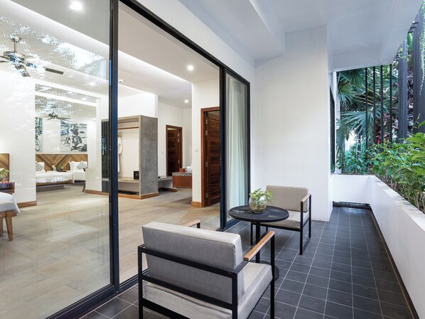 A modern interior with a seating area, a dining table, and a view of a lush garden through a glass wall.
