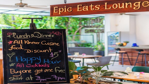 Eine Kreidetafel im Epic Eats Lounge wirbt mit Mittag- und Abendessen, ausschließlich Khmer-Küche, einem Rabatt von 15%, Happy Hour, allen Cocktails sowie einem Aktion '2 für 1', beginnend um 15 Uhr.