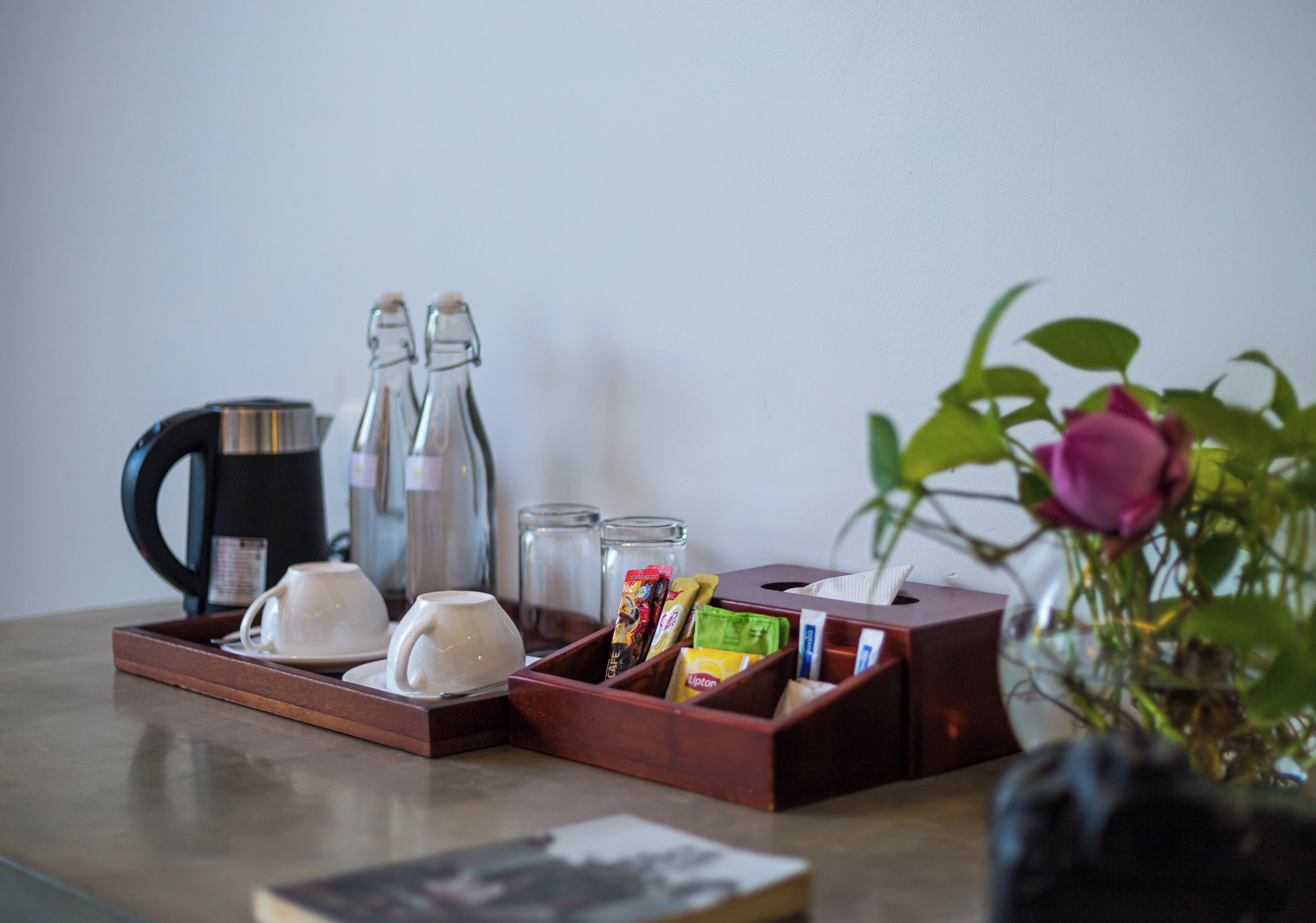 A tray with coffee cups, a coffee pot, sugar, and tea bags on a table.
