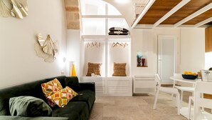 Ein modernes Wohnzimmer mit einem grünen Sofa, weißen Möbeln und einer Küchenzeile mit Esstisch und Stühlen.