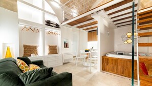 Ein modernes Wohnzimmer mit einem grünen Sofa, einem Essbereich mit weißen Stühlen und einer Küche mit Holzschränken.