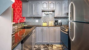 A modern kitchen with grey cabinets, a stainless steel refrigerator, and a tiled backsplash. - Historic 1B/1B Condo in Atlanta (Atlanta)