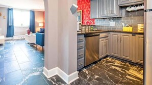 A modern kitchen with grey cabinets, a stainless steel dishwasher, and a red backsplash. - Historic 1B/1B Condo in Atlanta (Atlanta)