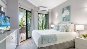 Un dormitorio con cama, escritorio, televisor y vista al mar.