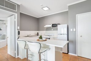 A modern kitchen with a central island, bar stools, and a microwave above the counter.