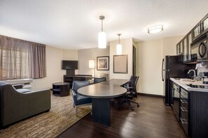 A modern living room with a large round table, a sofa, and a TV. - Modern Oasis in Plano, Texas! 2 Spacious Units, Full Kitchen, Pets Allowed! (Plano)