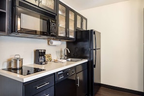 A modern kitchen with a black refrigerator, a coffee maker, and a stainless steel pot on the counter. - Modern Oasis in Plano, Texas! 2 Spacious Units, Full Kitchen, Pets Allowed! (Plano)