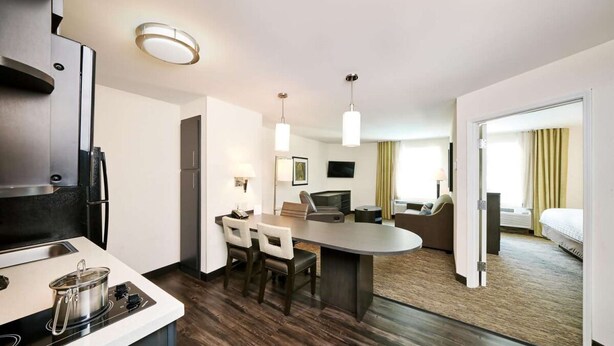 A modern hotel room with a kitchen area, a dining table, and a separate living area. - Modern Oasis in Plano, Texas! 2 Spacious Units, Full Kitchen, Pets Allowed! (Plano)