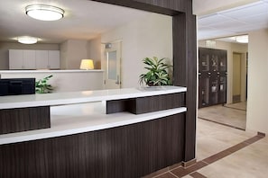 A reception desk with a modern design, a potted plant, and a sign indicating a waiting area. - Modern Oasis in Plano, Texas! 2 Spacious Units, Full Kitchen, Pets Allowed! (Plano)