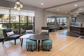 Ein stilvoller Lounge-Bereich mit großen Fenstern, bequemen Sitzmöglichkeiten und einem zentralen Tisch.