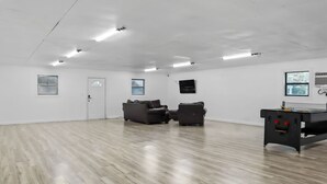 A spacious room with a wooden floor, two sofas, a table with a pool table, and a door. - Mathis Motel (Mathis)