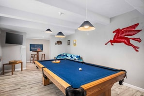 A pool table in a room with a wooden floor, a red dragon wall decoration, and a TV mounted on the wall. - Outstanding Ocean Front Home, Pet Friendly, Hot Tub, Pool Table, Games, Seconds From Beach (Rockaway Beach)