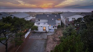 A residential area with houses, a driveway, and a sunset over the ocean. - Outstanding Ocean Front Home, Pet Friendly, Hot Tub, Pool Table, Games, Seconds From Beach (Rockaway Beach)
