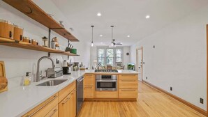 A modern kitchen with wooden cabinets, a white countertop, and stainless steel appliances. - The Urban Oasis - 3 BR - Great Location (Columbus)