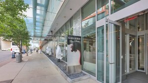 A modern building with a glass facade, a sign for 'Gallerie Bar & Bistro', and a pedestrian walkway. - The Urban Oasis - 3 BR - Great Location (Columbus)