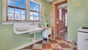 Una cocina con un lavamanos antiguo, encimera de madera y pared de ladrillo.