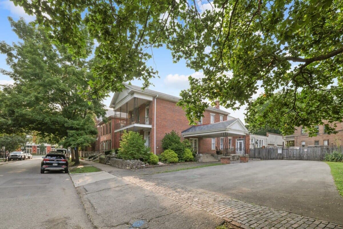 A residential street with brick houses, a driveway, and parked cars.