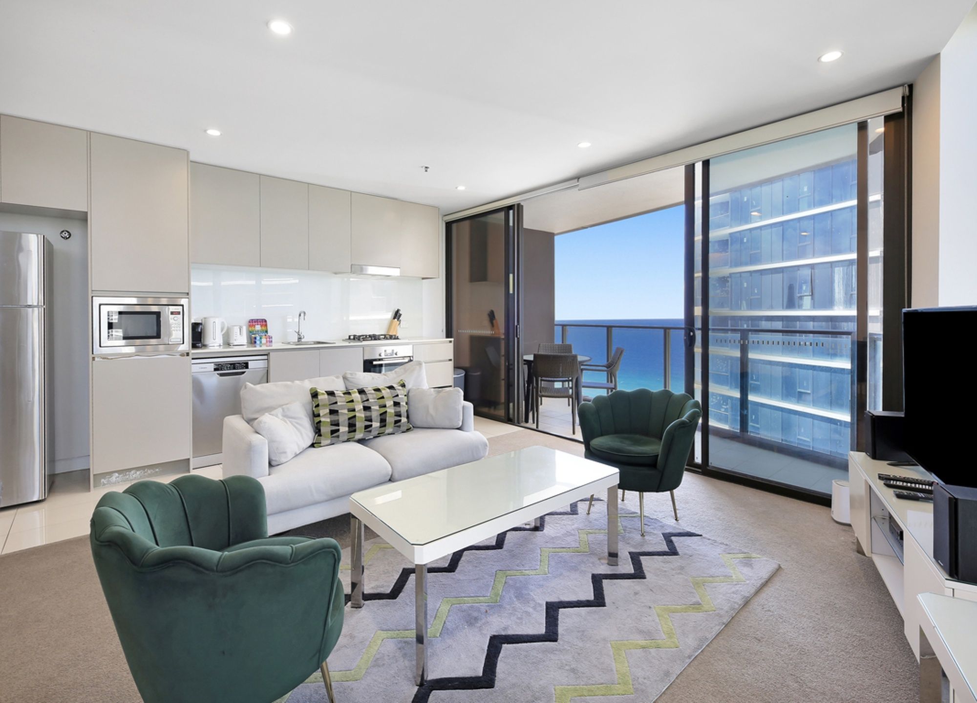 A modern apartment with a kitchen, living area, and balcony with a city view.