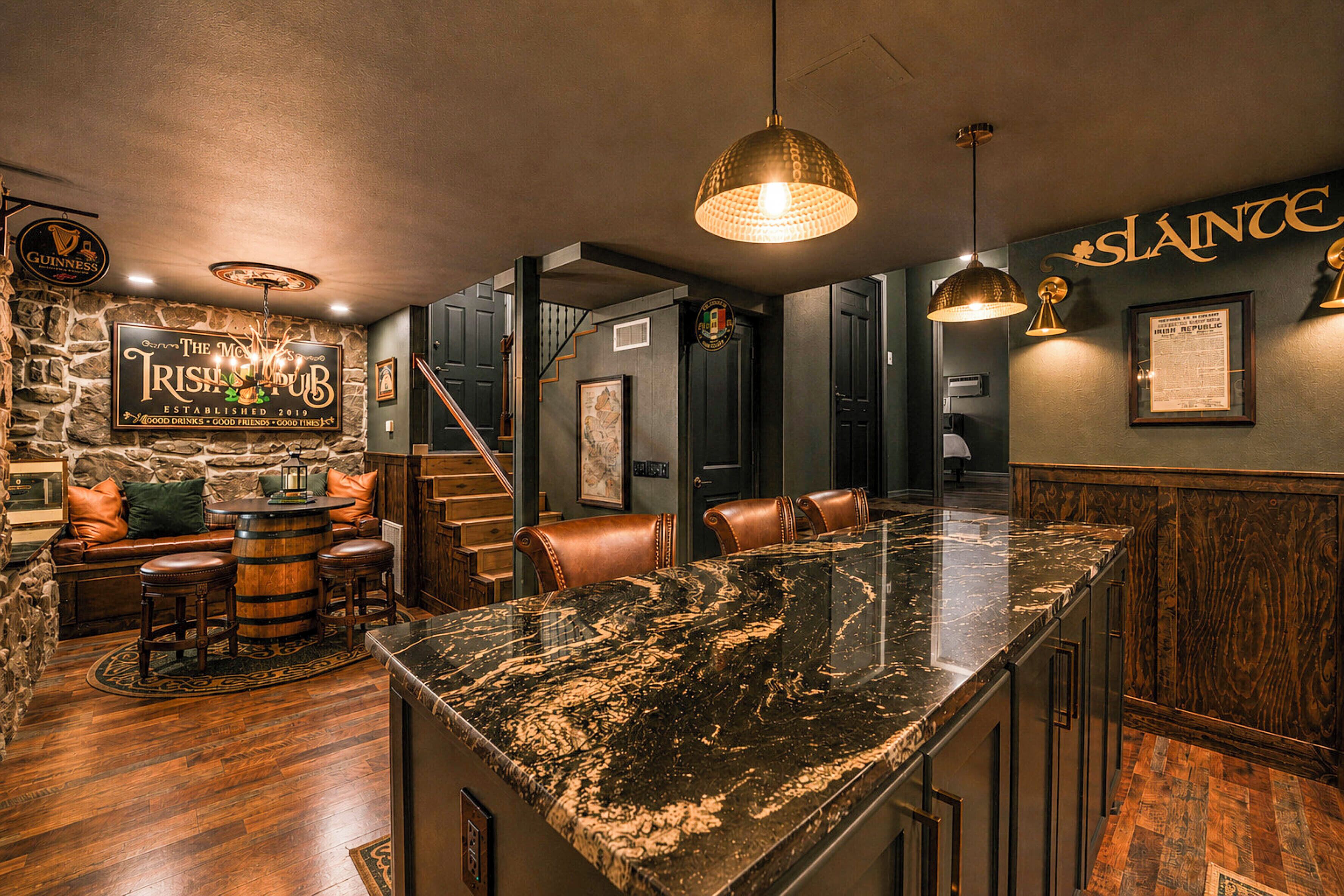 Un espace bar avec un mur en pierre, des tabourets de bar en bois et un comptoir en marbre.