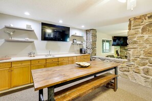 Enjoy meals at the kitchen table with a bench, surrounded by a stone wall and a flat-screen TV.