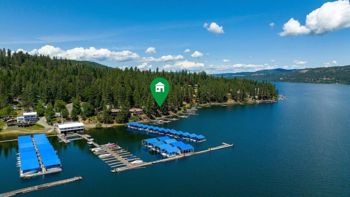 A lakeside property with a dock, boats, and cabins.