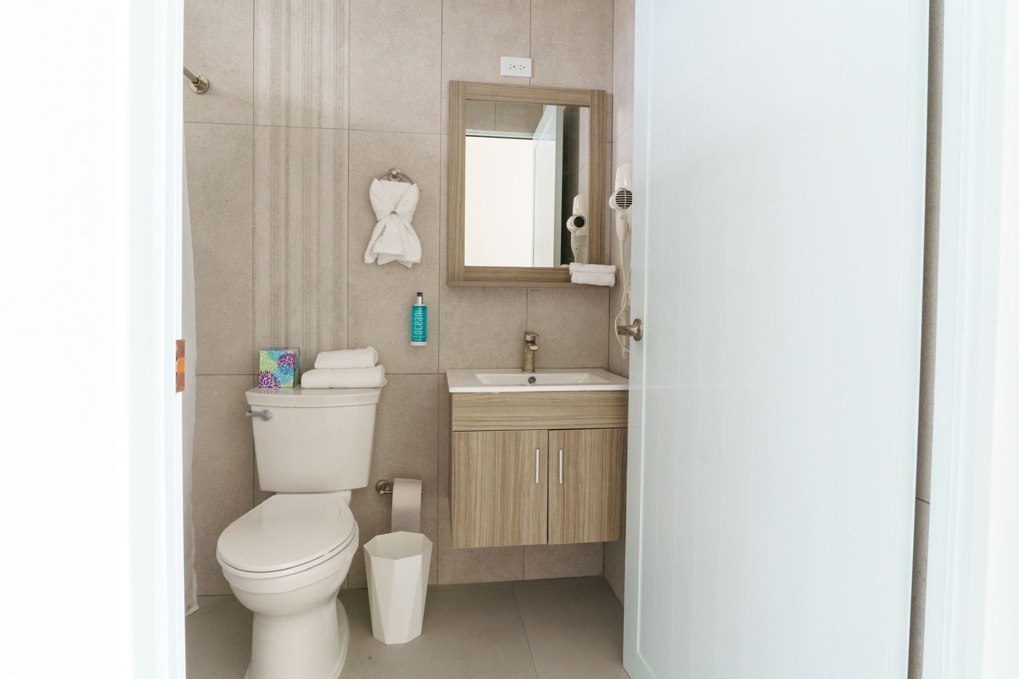 Un bagno con il water, un lavandino, uno specchio e un portascopino.