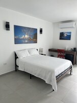 Un dormitorio moderno con una cama, un escritorio y dos altavoces integrados en la pared.