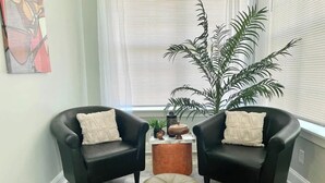 A living room with two black leather armchairs, a round copper side table, and a large potted plant. - Charming Retreat | Walkable • Private Fenced Yard (Indianapolis)