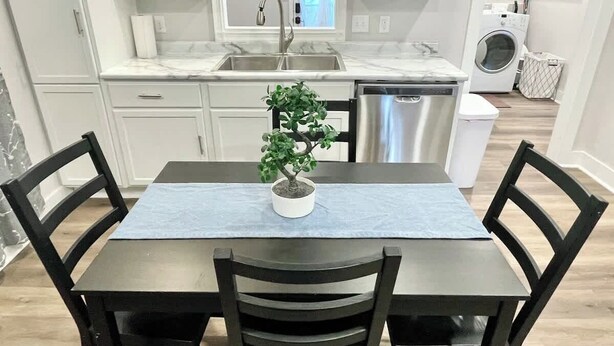 A dining area with a table set for four, a potted plant, and a kitchen in the background. - Newly Remodeled 2 Bedroom Home in Shelbyville! (Shelbyville)
