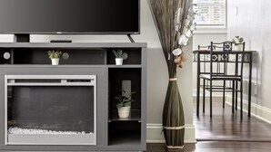 Una sala de estar con una televisión de pantalla plana, una chimenea y un comedor con sillas y una mesa.