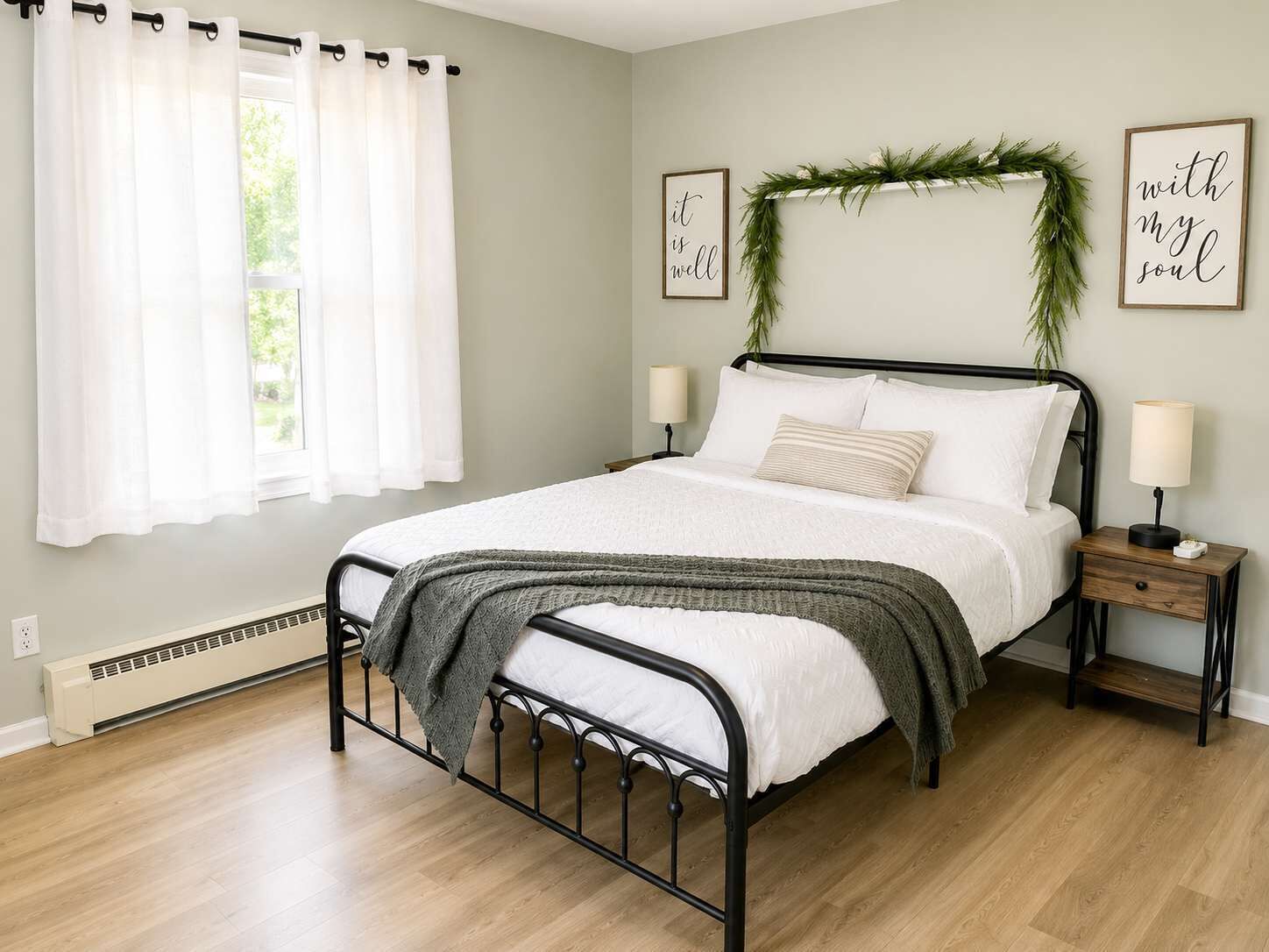A neatly arranged bedroom with a bed, two bedside tables, a window with curtains, and wall decorations.