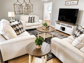 A living room with a sofa, two coffee tables, a TV, and decorative items.