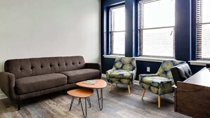 A living room with a brown sofa, two armchairs, a coffee table, and a wooden side table. - Theatre District Condo | Gym • Free Parking • DT (Louisville)