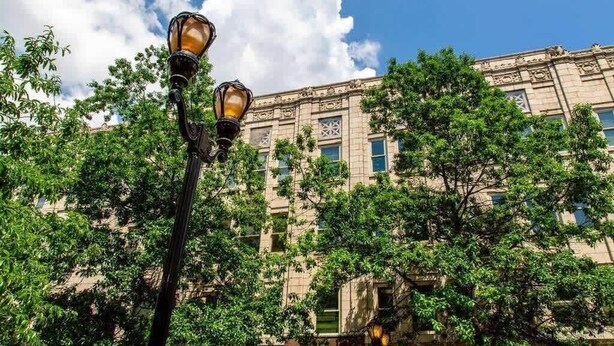A street lamp in front of a building with ornate architecture and trees. - Theatre District Condo | Gym • Free Parking • DT (Louisville)