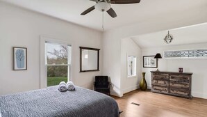 Un dormitorio con cama, ventilador de techo, cómoda y ventana.
