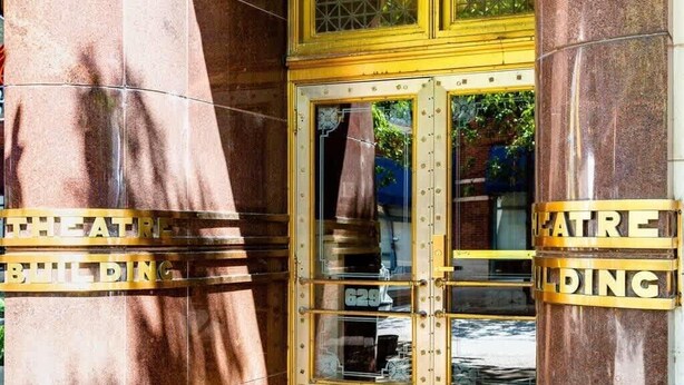 A theater entrance with a golden door and columns. - Modern 2BR Luxury Condo • Downtown w/ Garage & Gym (Louisville)
