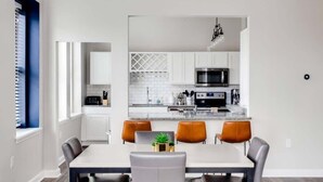 A modern kitchen with white cabinets, a microwave, and a dining area with a table and chairs. - Modern 2BR Luxury Condo • Downtown w/ Garage & Gym (Louisville)