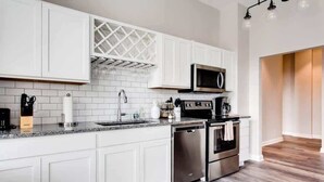 A modern kitchen with white cabinets, a stainless steel dishwasher, an oven, and a microwave. - Modern 2BR Luxury Condo • Downtown w/ Garage & Gym (Louisville)