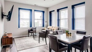 A modern living room with a sofa, chairs, a dining table, and a ceiling fan. - Modern 2BR Luxury Condo • Downtown w/ Garage & Gym (Louisville)