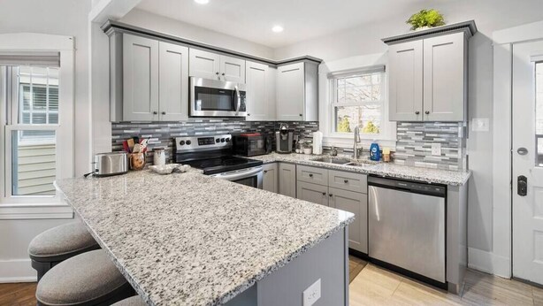 A modern kitchen with granite countertops, stainless steel appliances, and white cabinetry.