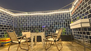 An outdoor seating area with a curved wall, string lights, and potted plants. - 8h - Hostel  (Ho Chi Minh City)