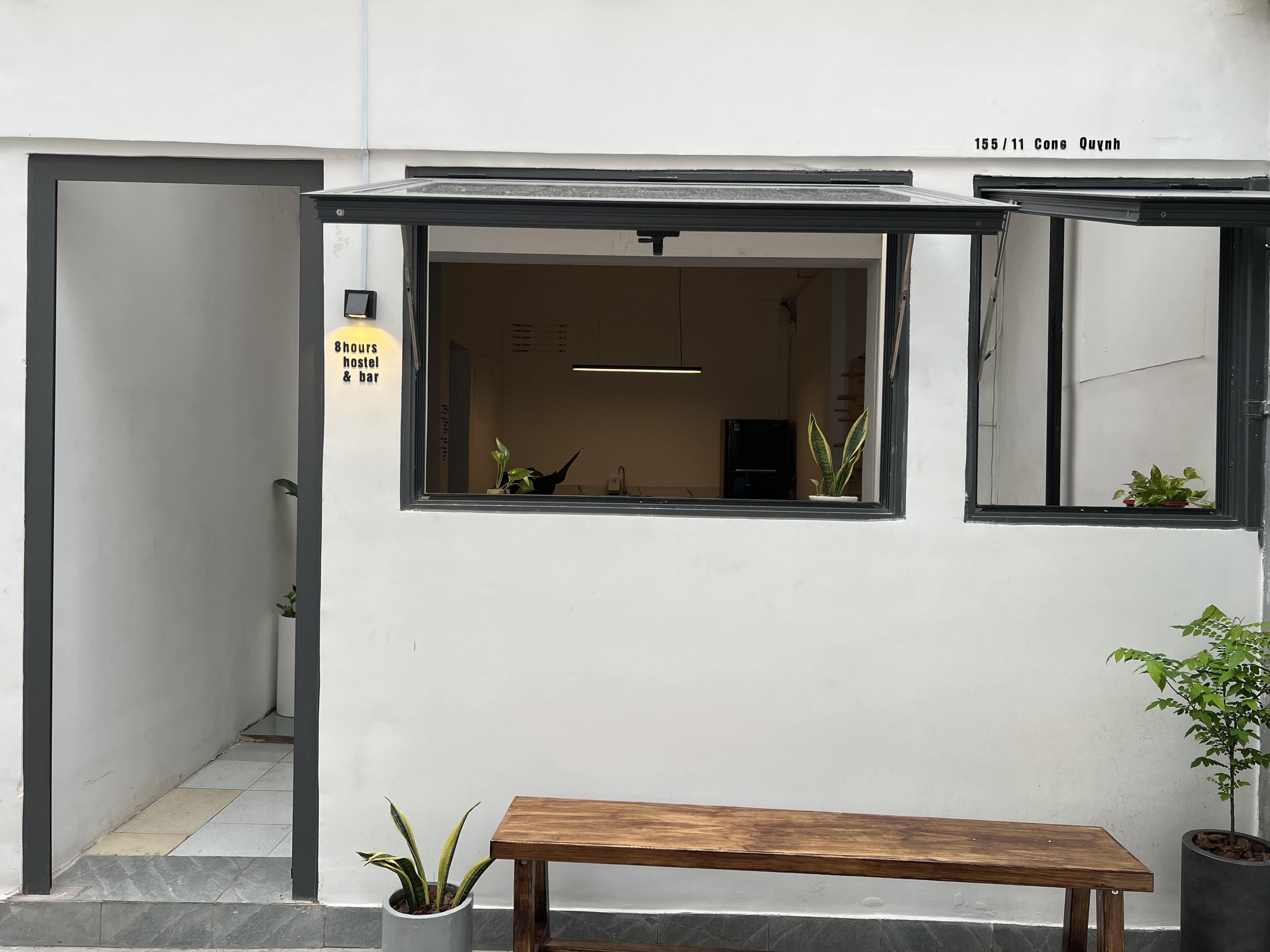 A modern building with a large window, a bench outside, and a sign indicating a hostel and bar.