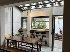 Un comedor con mesa y sillas de madera, un ventanal con vistas al exterior y un techo con diseño de cuadrícula.