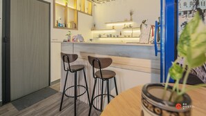 A modern kitchen with bar stools, a counter, and a hanging light fixture. - 8h - Hostel  (Ho Chi Minh City)