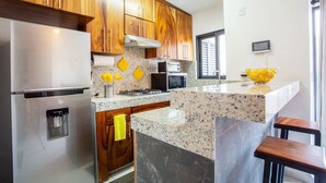 A modern kitchen with wooden cabinets, stainless steel appliances, a granite countertop, and a yellow towel hanging on the door. - Beautiful Casa Madero 470 (Puerto Vallarta)