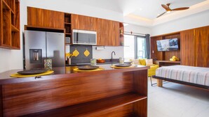 Una cocina moderna con armarios de madera, microondas integrado y televisor de pantalla plana.