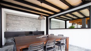 Un comedor con una mesa y sillas de madera, una lámpara colgante y una pared de piedra.