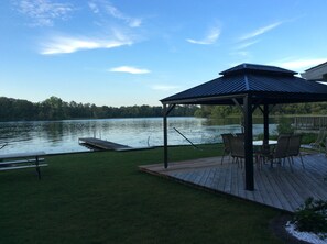 A gazebo with a view of a lake, a dock, and a grassy deck with chairs. - Cozy little cottage on beautiful Pine Lake (Plainwell)