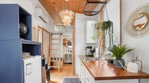 Una cocina moderna con armarios de madera, un refrigerador empotrado, una encimera de madera y una lámpara colgante.